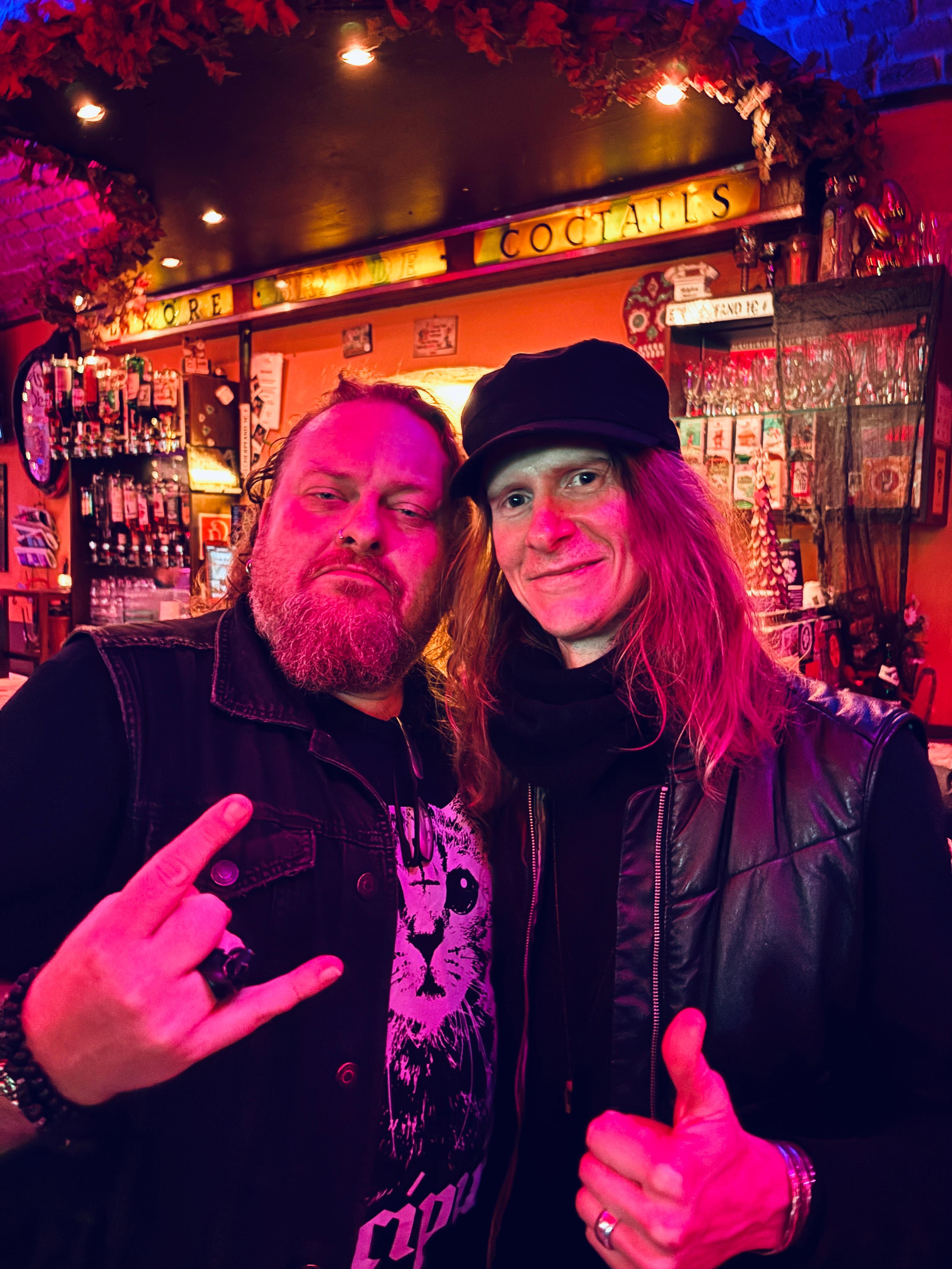Adam und Zoltan zeigen Rockerzeichen an der Bar